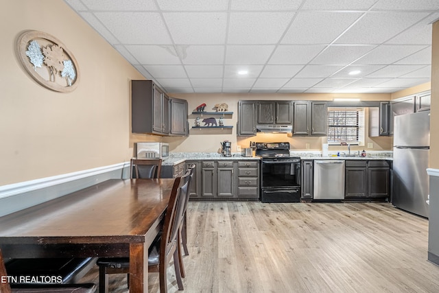 kitchen with a paneled ceiling, stainless steel appliances, light hardwood / wood-style floors, and sink