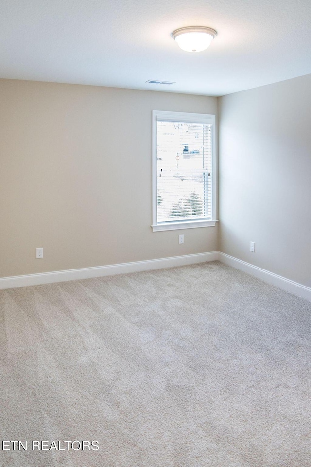 empty room with carpet flooring, visible vents, and baseboards