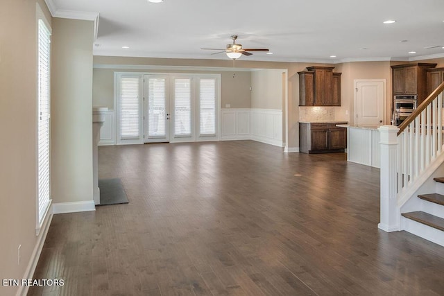 unfurnished living room with dark wood-type flooring, ornamental molding, stairway, and ceiling fan