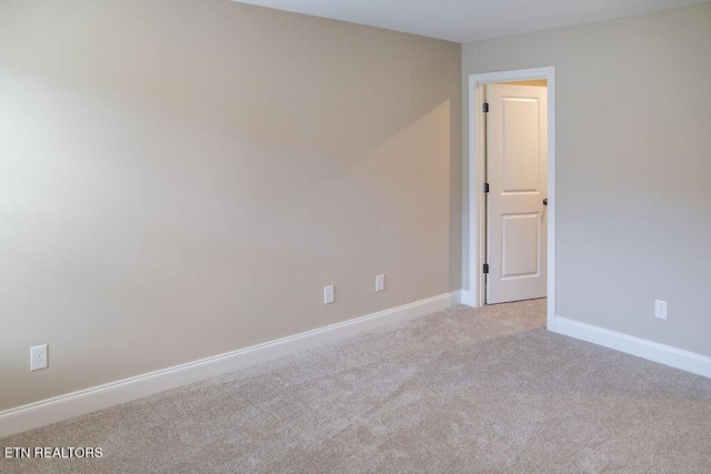 carpeted empty room featuring baseboards