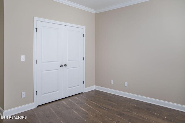 unfurnished bedroom featuring a closet, baseboards, dark wood finished floors, and crown molding