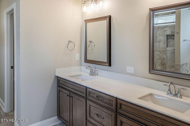 full bathroom with double vanity, baseboards, and a sink