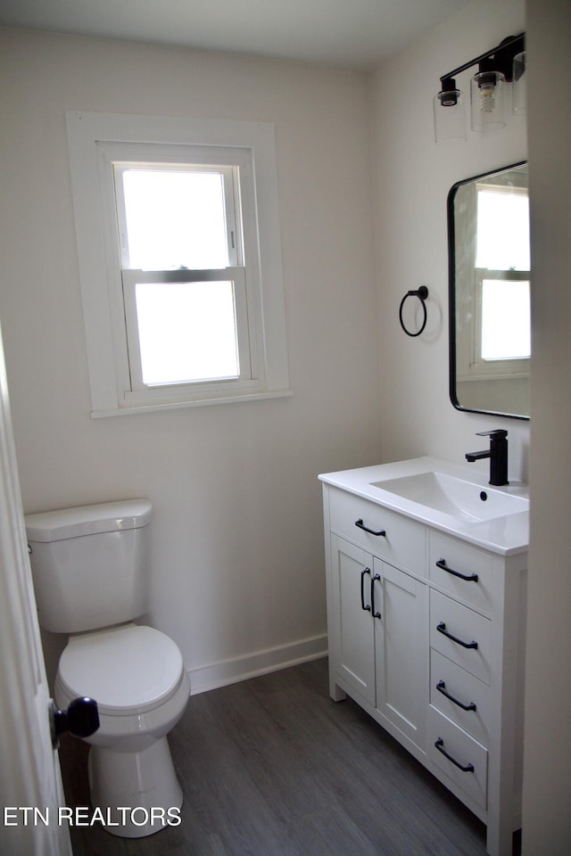 bathroom with vanity, hardwood / wood-style flooring, a wealth of natural light, and toilet