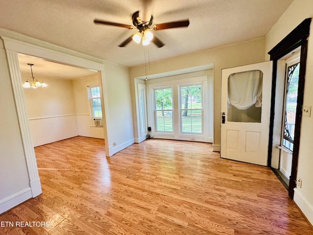 interior space featuring ceiling fan with notable chandelier, light hardwood / wood-style floors, and a textured ceiling