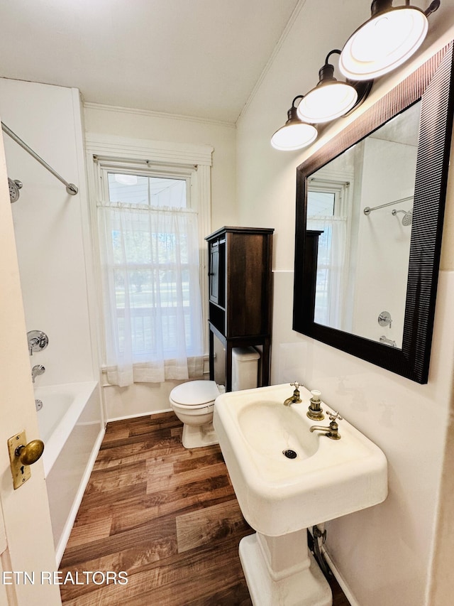 bathroom with hardwood / wood-style flooring, ornamental molding, shower / washtub combination, and toilet