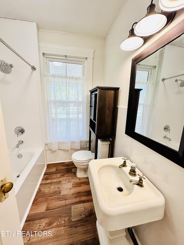 full bathroom featuring sink, crown molding, hardwood / wood-style flooring, bathing tub / shower combination, and toilet