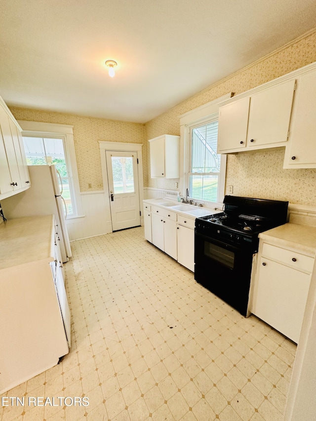 kitchen with black range oven, sink, and white cabinets