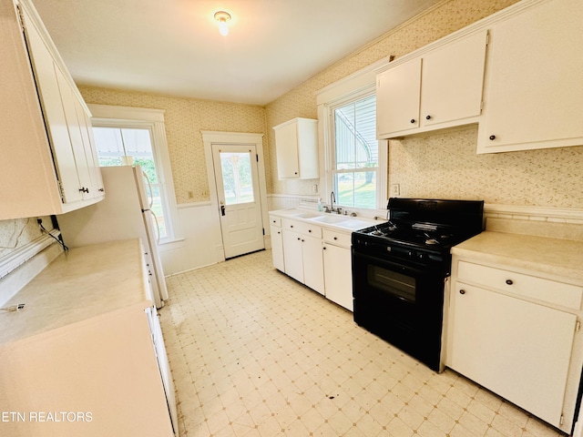 kitchen featuring white cabinetry, black range, and sink