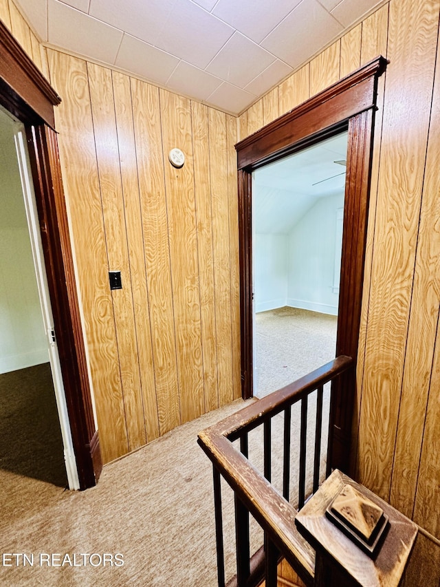 corridor featuring carpet and wood walls