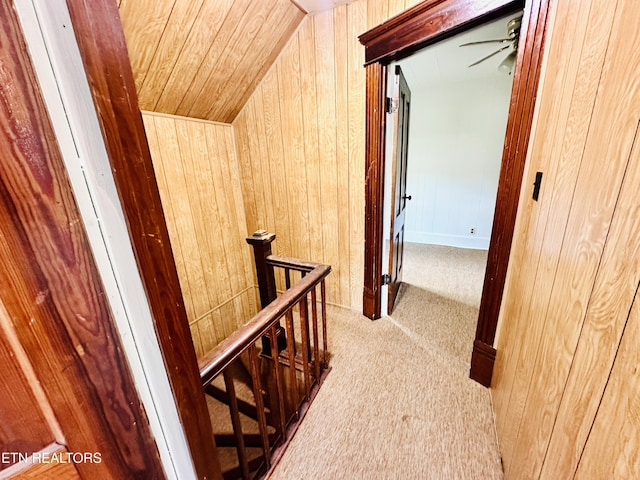 hallway featuring wood ceiling, light colored carpet, lofted ceiling, and wood walls