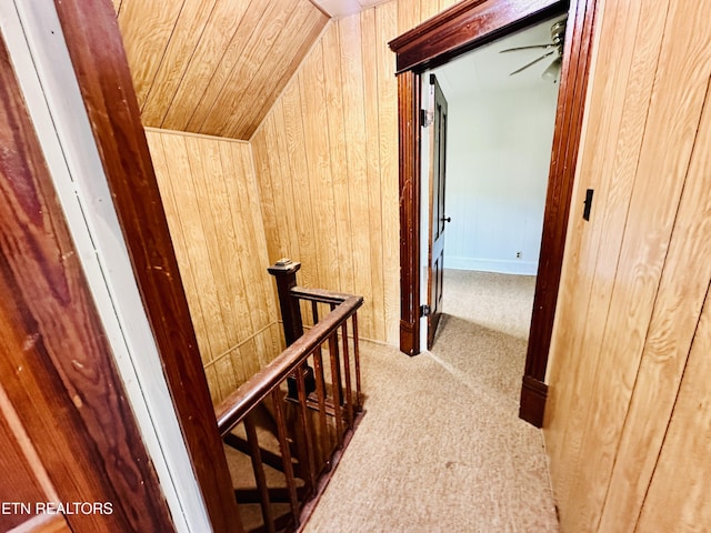 hallway featuring vaulted ceiling, light colored carpet, wood ceiling, and wooden walls