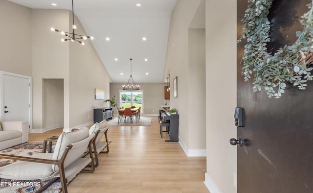 living room with high vaulted ceiling, a chandelier, and light hardwood / wood-style floors