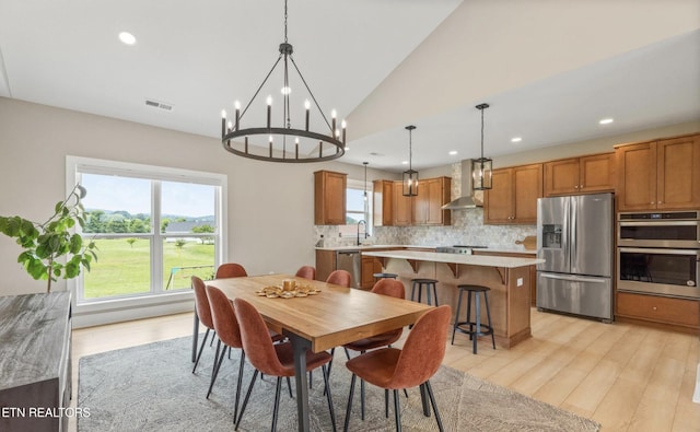 dining space featuring vaulted ceiling, sink, a wealth of natural light, and light hardwood / wood-style flooring