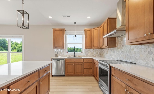 kitchen with pendant lighting, wall chimney range hood, stainless steel appliances, and sink