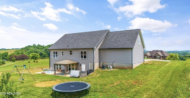 rear view of house featuring a trampoline, central AC unit, a gazebo, and a lawn