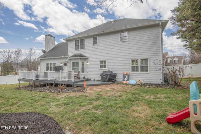 back of house featuring a playground, a yard, a deck, and a patio area