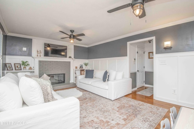 living room with a fireplace, crown molding, light hardwood / wood-style flooring, and ceiling fan