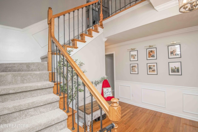 staircase featuring hardwood / wood-style flooring, ornamental molding, and a high ceiling