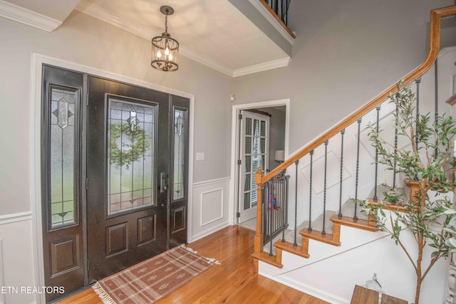 entryway featuring hardwood / wood-style flooring, crown molding, and a notable chandelier