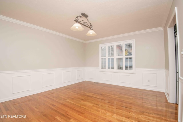 unfurnished room with an inviting chandelier, ornamental molding, and light hardwood / wood-style floors