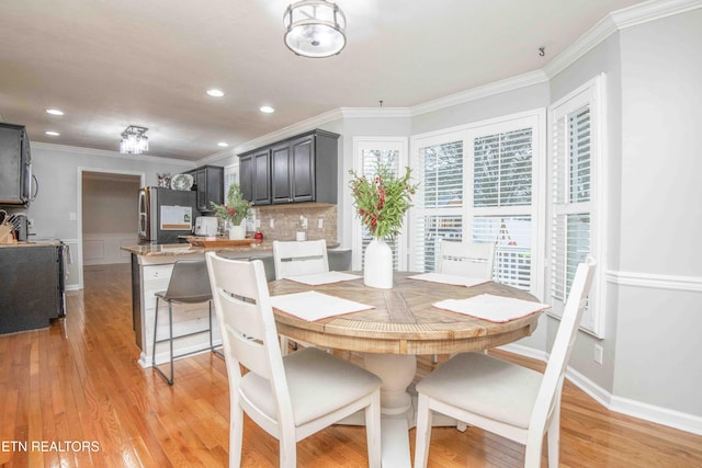 dining space with crown molding and light hardwood / wood-style flooring