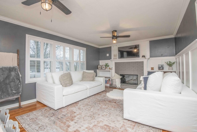 living room featuring hardwood / wood-style flooring, a fireplace, ornamental molding, and ceiling fan