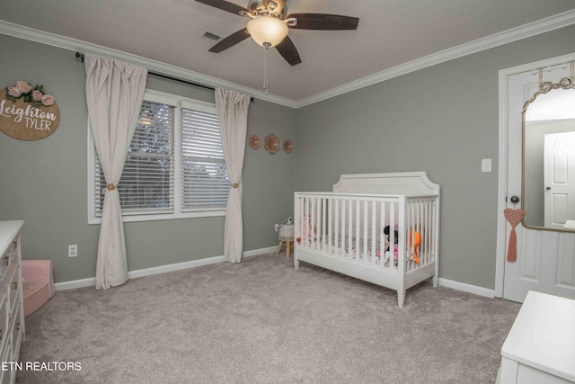 carpeted bedroom featuring ornamental molding, a nursery area, and ceiling fan