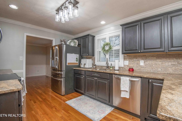 kitchen featuring light stone counters, stainless steel appliances, sink, and light wood-type flooring