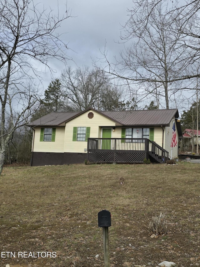 view of front of home with a front lawn, crawl space, metal roof, and a wooden deck