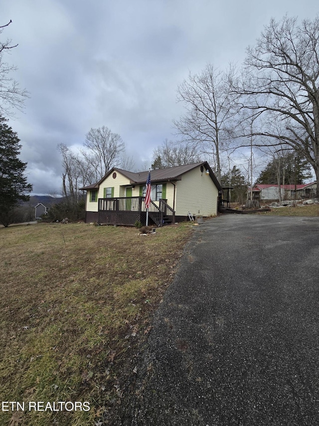 bungalow-style house featuring a deck and a front lawn