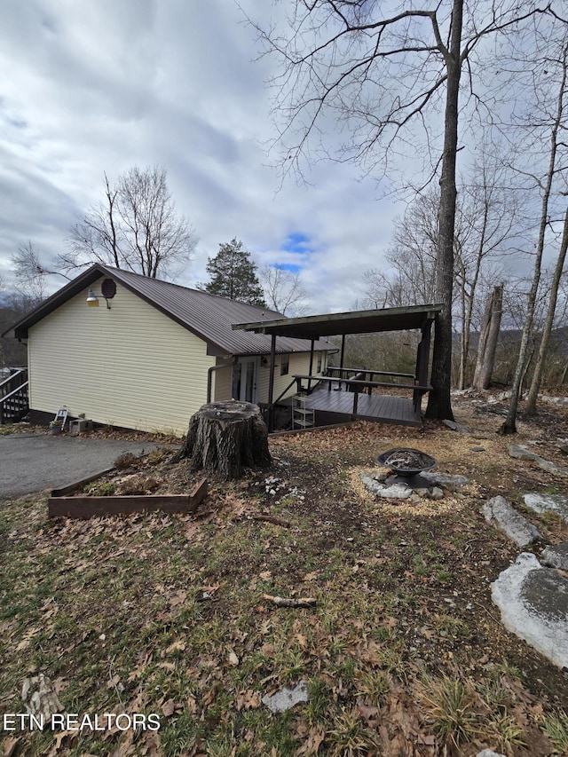 view of property exterior with aphalt driveway, metal roof, and a wooden deck