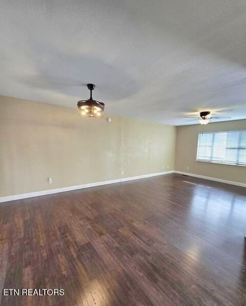 spare room featuring baseboards, dark wood finished floors, and a ceiling fan