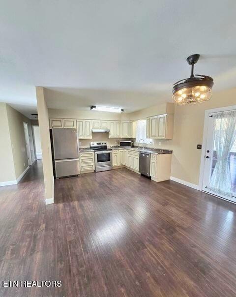 kitchen featuring stainless steel appliances, cream cabinetry, dark wood-type flooring, and under cabinet range hood