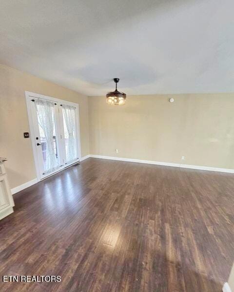 empty room featuring an inviting chandelier, baseboards, and dark wood-type flooring