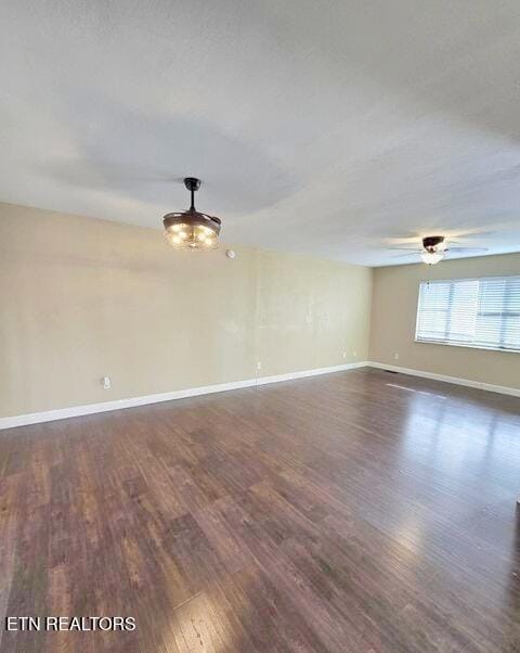 unfurnished room with dark wood finished floors, a ceiling fan, and baseboards