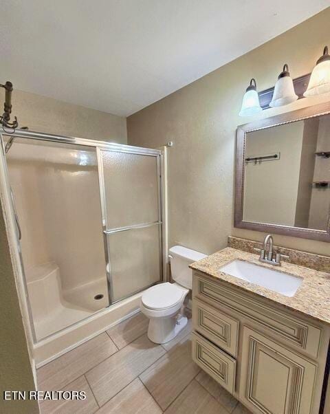 bathroom with a stall shower, vanity, and toilet