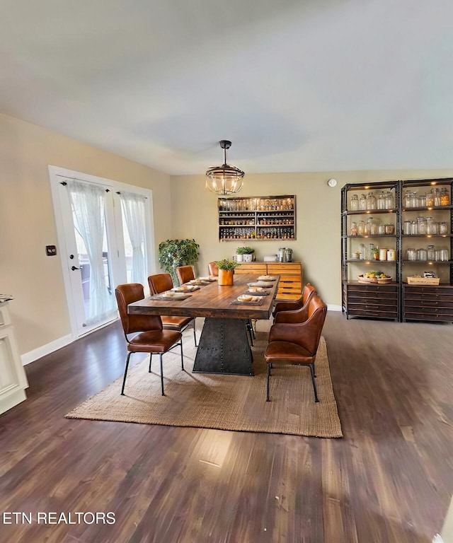 dining room featuring a chandelier, baseboards, and wood finished floors