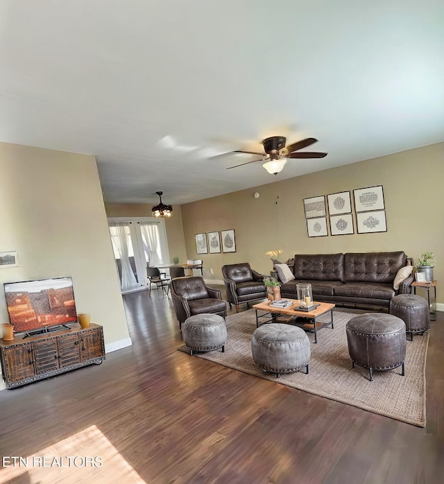 living area featuring baseboards, wood finished floors, and ceiling fan with notable chandelier