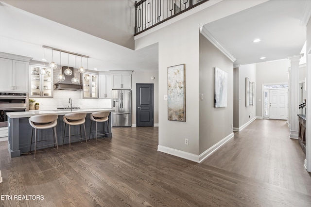 kitchen featuring a breakfast bar, a center island with sink, appliances with stainless steel finishes, dark hardwood / wood-style flooring, and pendant lighting