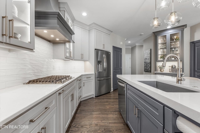 kitchen featuring sink, custom exhaust hood, gray cabinetry, hanging light fixtures, and stainless steel appliances