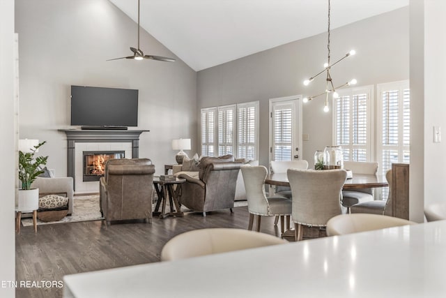 dining room featuring dark hardwood / wood-style flooring, high vaulted ceiling, ceiling fan, and a fireplace