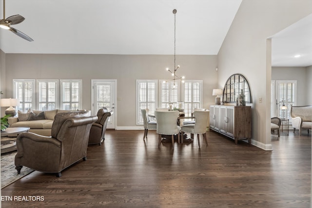 dining room featuring ceiling fan with notable chandelier, high vaulted ceiling, dark hardwood / wood-style floors, and a healthy amount of sunlight