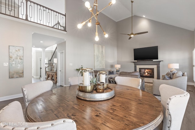 dining room featuring wood-type flooring, high vaulted ceiling, ceiling fan, and a fireplace