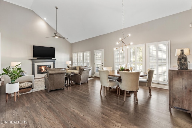 dining area with ceiling fan with notable chandelier, dark hardwood / wood-style floors, and high vaulted ceiling