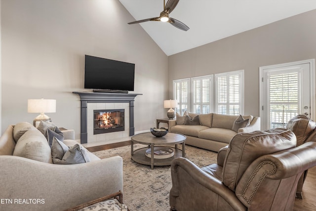 living room with a fireplace, high vaulted ceiling, ceiling fan, and light wood-type flooring