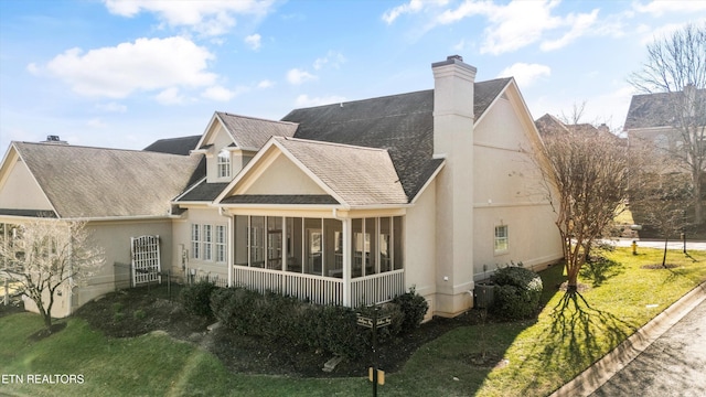 rear view of property featuring a sunroom and a lawn