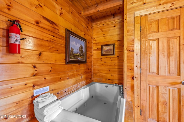 bathroom featuring wooden walls, a bath, wood ceiling, and beam ceiling