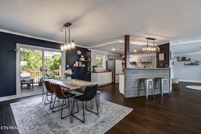 dining room with dark wood-type flooring, a wealth of natural light, and ornamental molding