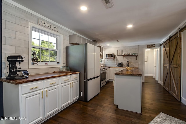 kitchen featuring wood counters, stainless steel appliances, a barn door, and white cabinets