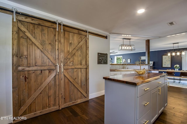 kitchen featuring wood counters, a barn door, decorative light fixtures, and a kitchen island